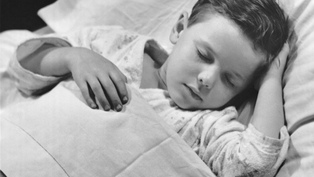Young boy asleep in bed gutt i seng med sengevæting